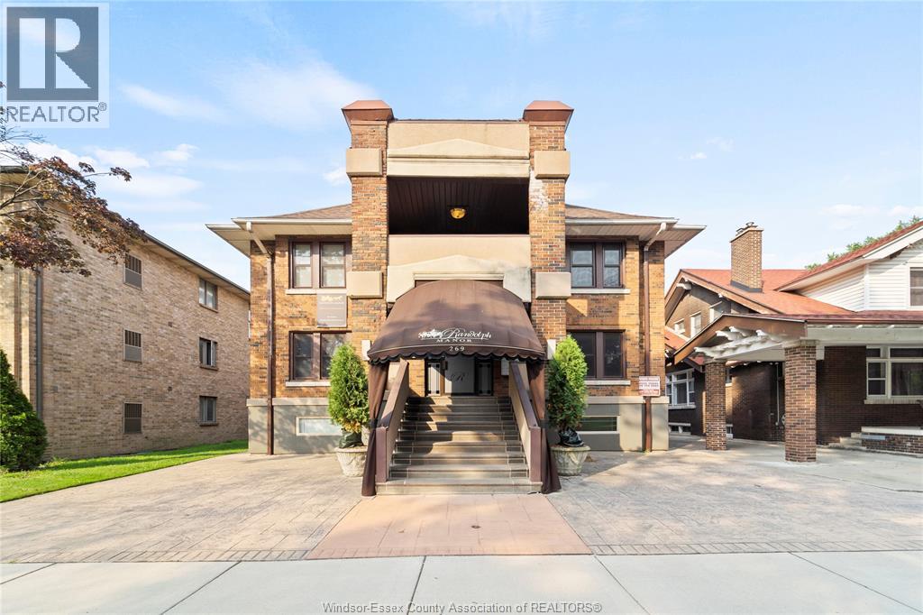 A large house with a stone wall and a covered entrance.