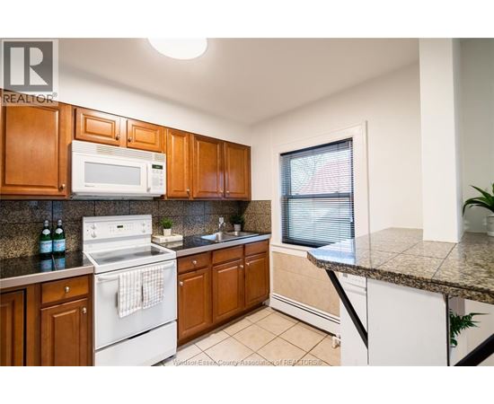 A kitchen with wooden cabinets and a white stove top oven.
