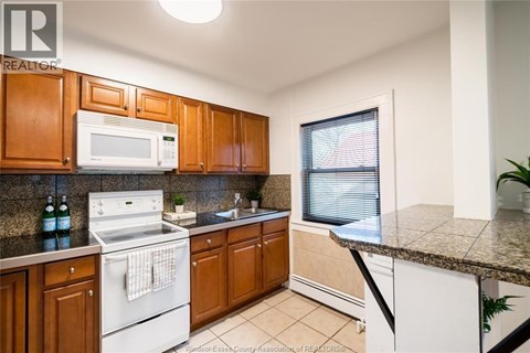 A kitchen with wooden cabinets and a white stove top oven.