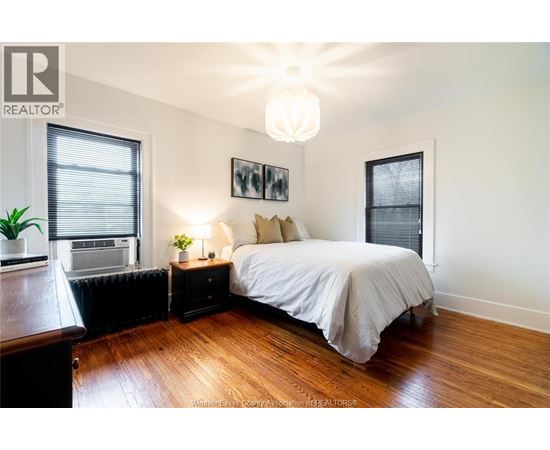 A bedroom with a large bed and a wooden floor.