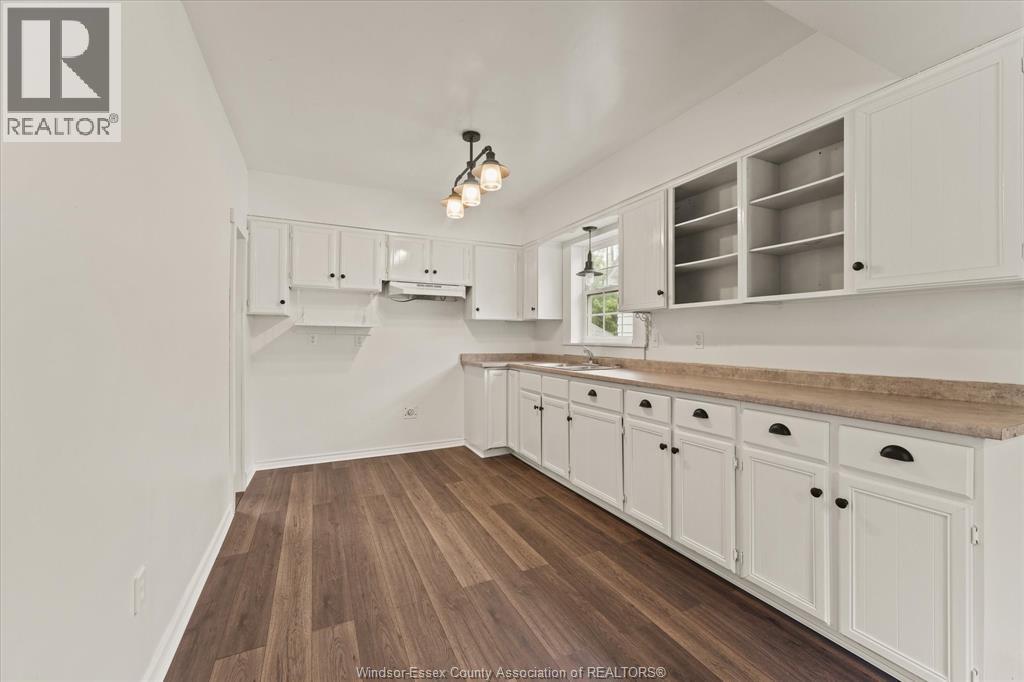 A kitchen with white cabinets and a wooden floor.