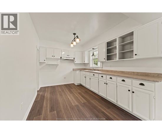 A kitchen with white cabinets and a wooden floor.