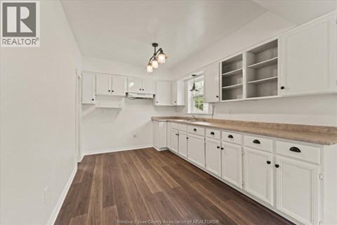 A kitchen with white cabinets and a wooden floor.