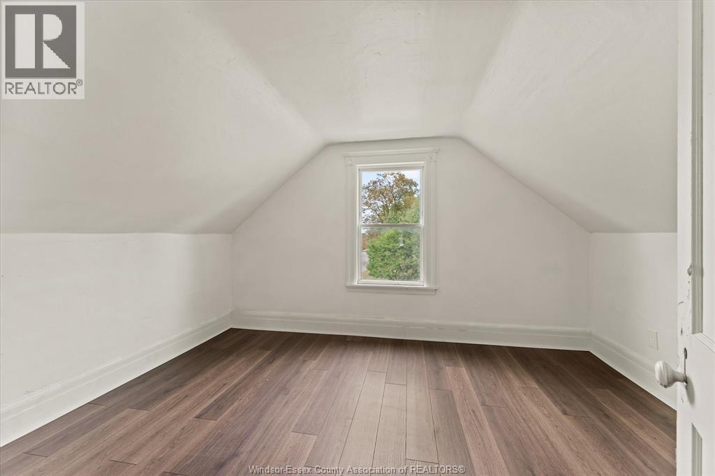 A room with wooden flooring and a window showing trees outside.