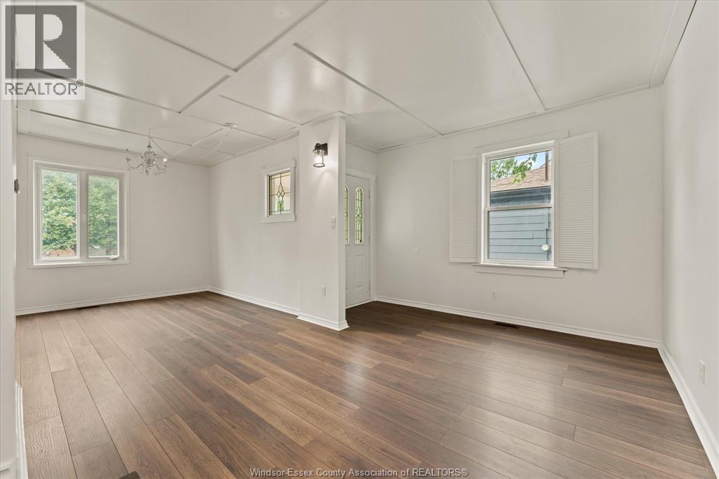 A spacious room with wooden flooring and white walls.