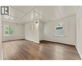 A spacious room with wooden flooring and white walls.