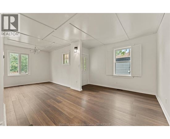 A spacious room with wooden flooring and white walls.