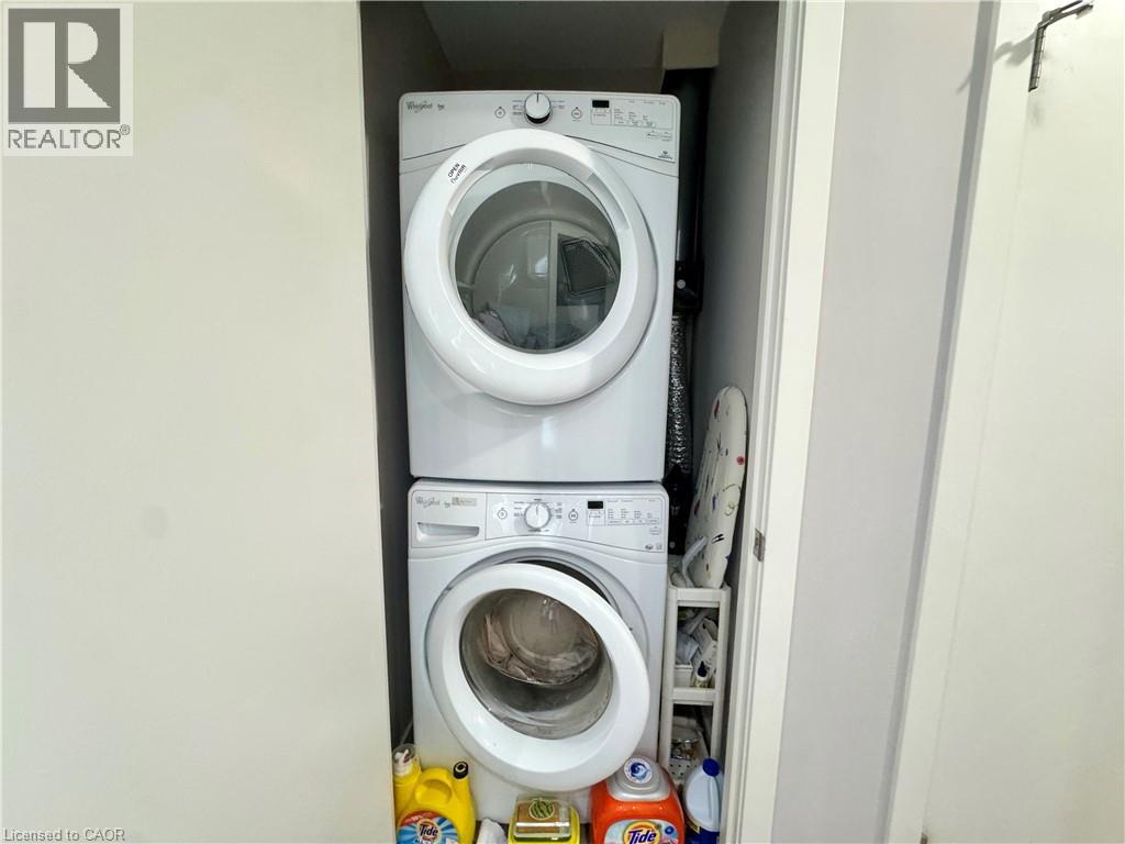 A white washing machine is stacked on top of another in a small laundry space.