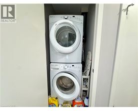 A white washing machine is stacked on top of another in a small laundry space.