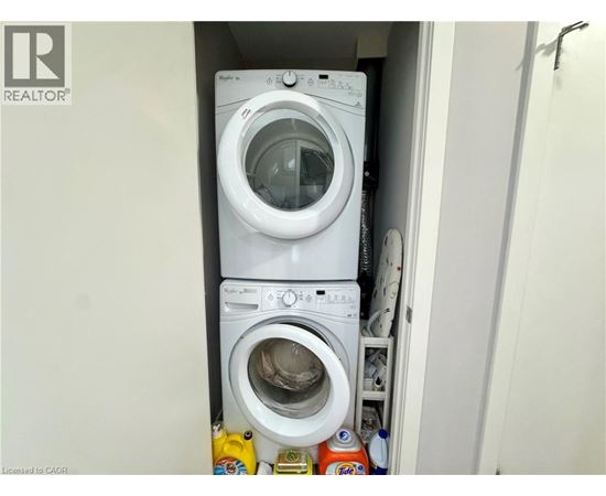 A white washing machine is stacked on top of another in a small laundry space.