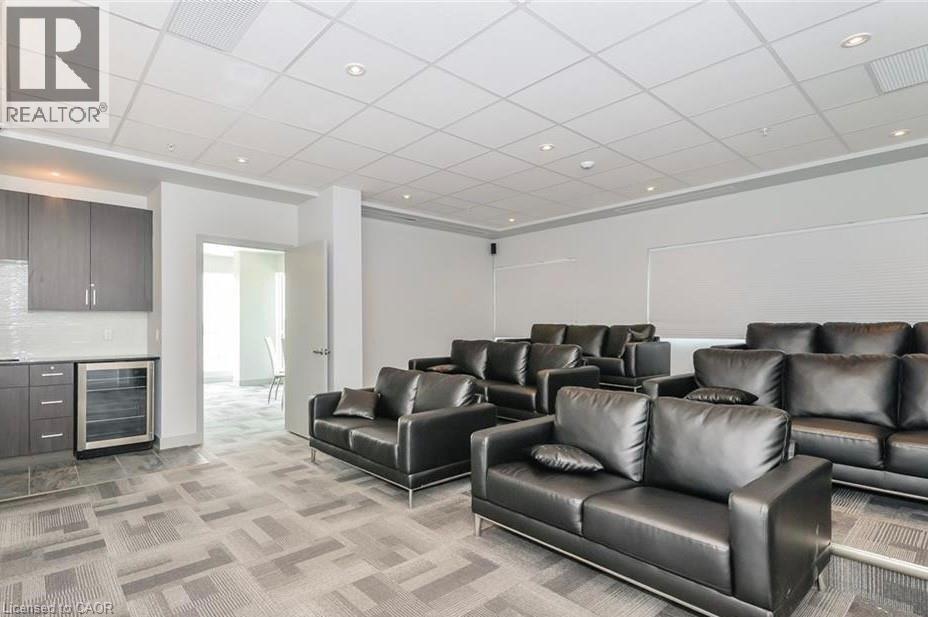 A living room with black leather couches and a grey carpet.