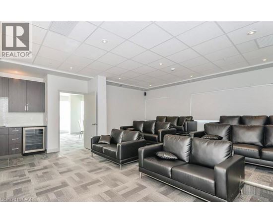 A living room with black leather couches and a grey carpet.