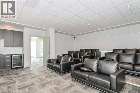 A living room with black leather couches and a grey carpet.