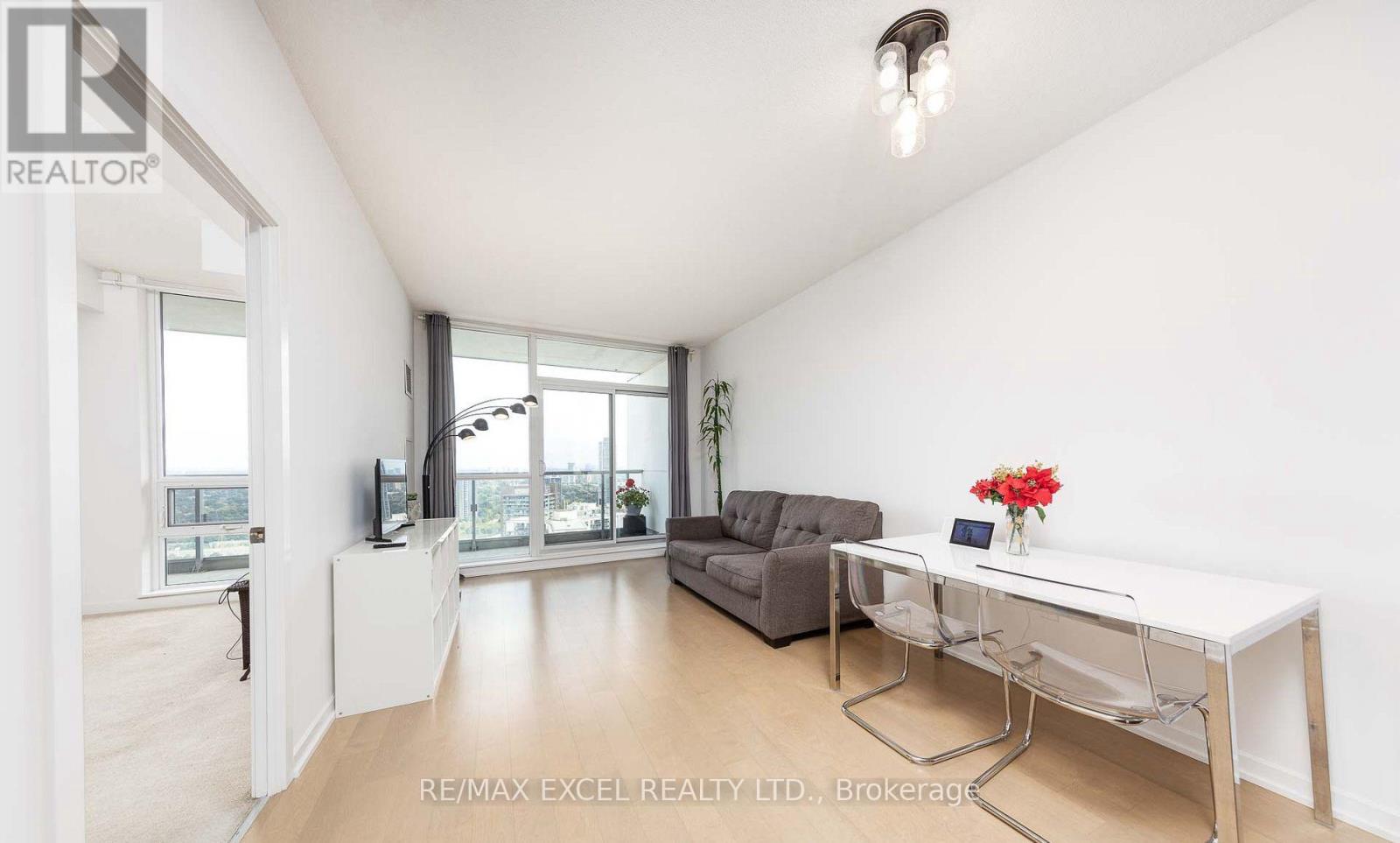 A realtor's office with a desk, couch, and a window overlooking a cityscape.