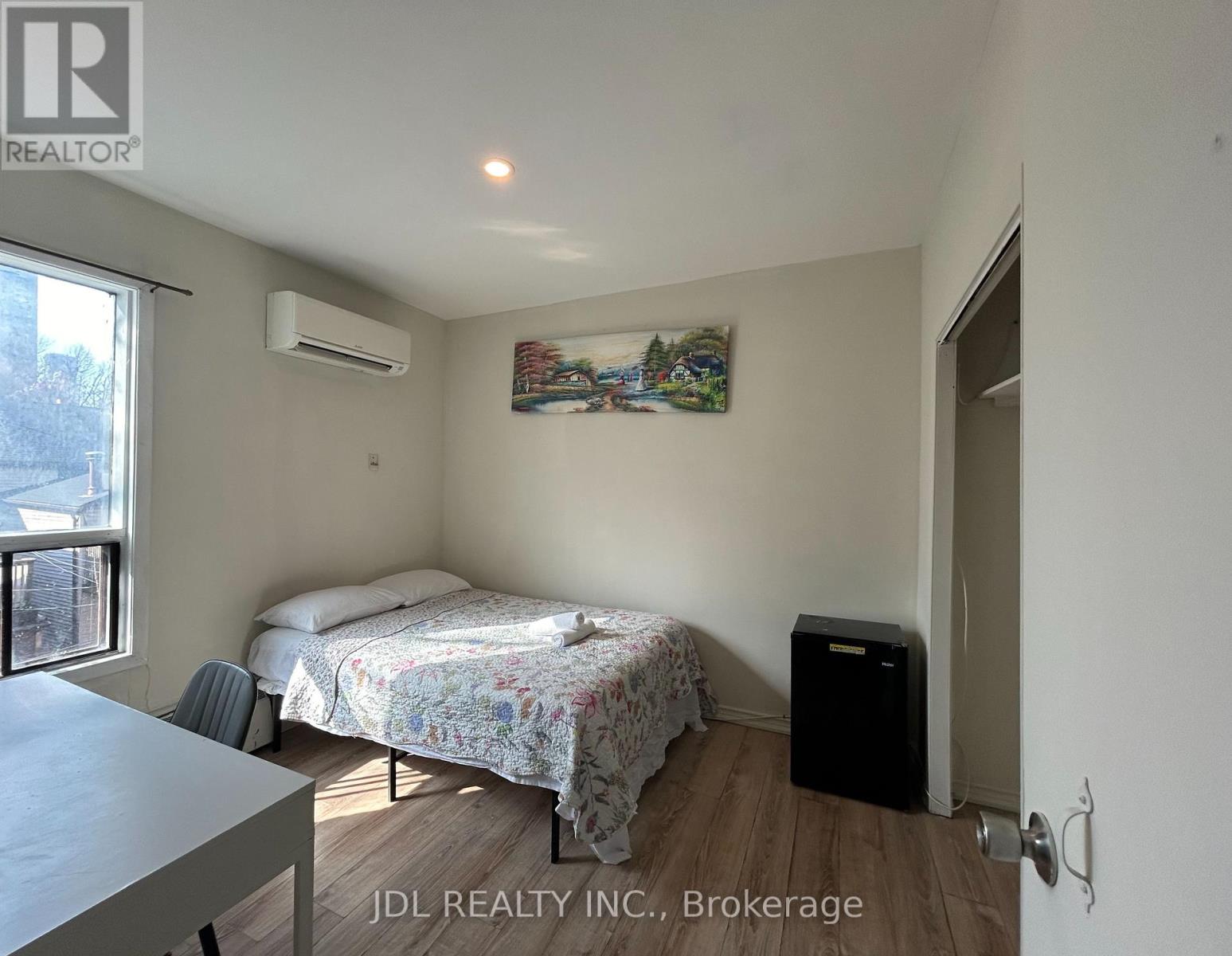 A bedroom with a bed, a chair, and a painting on the wall.