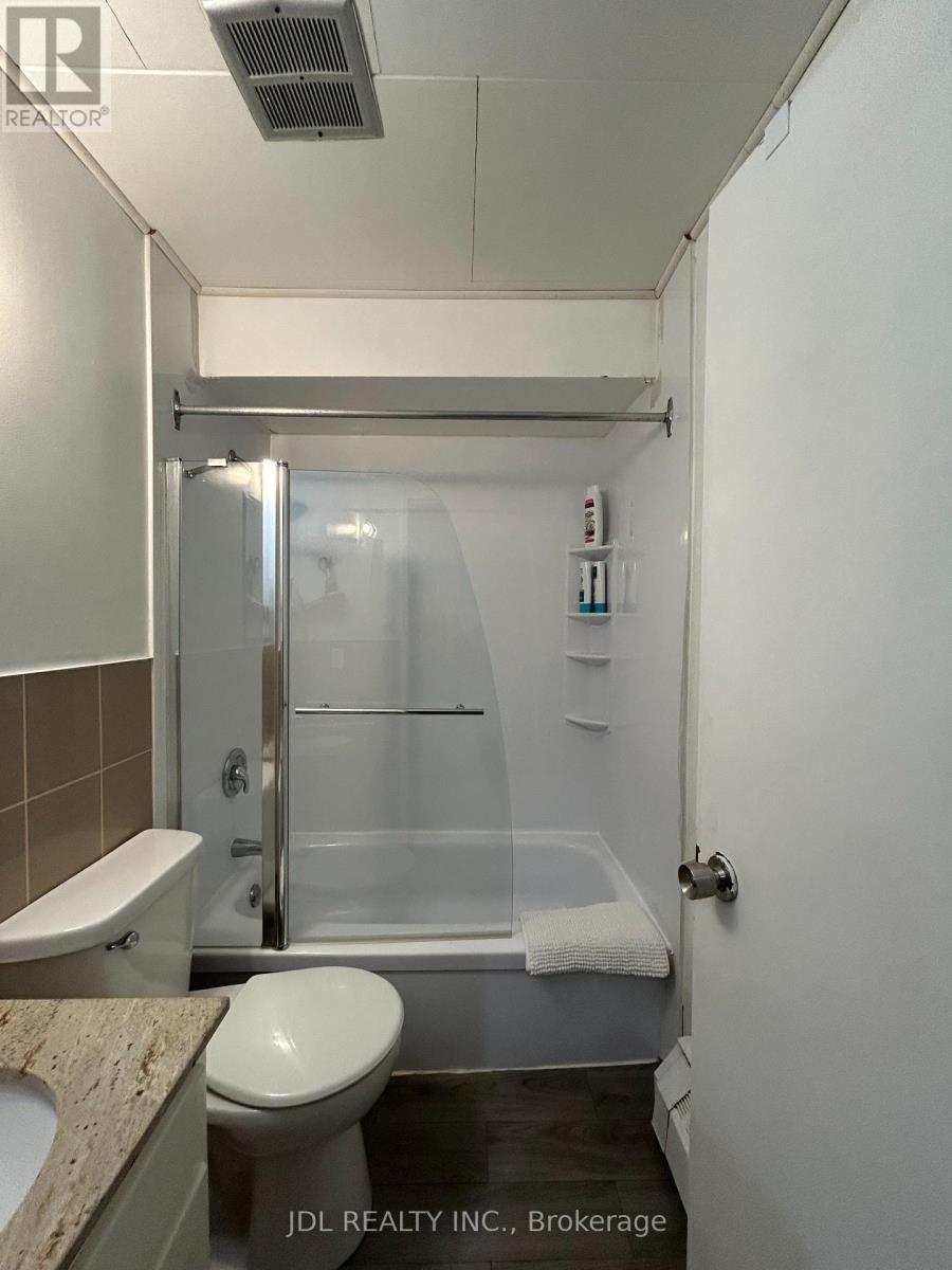 A small bathroom with a toilet, sink, and shower.