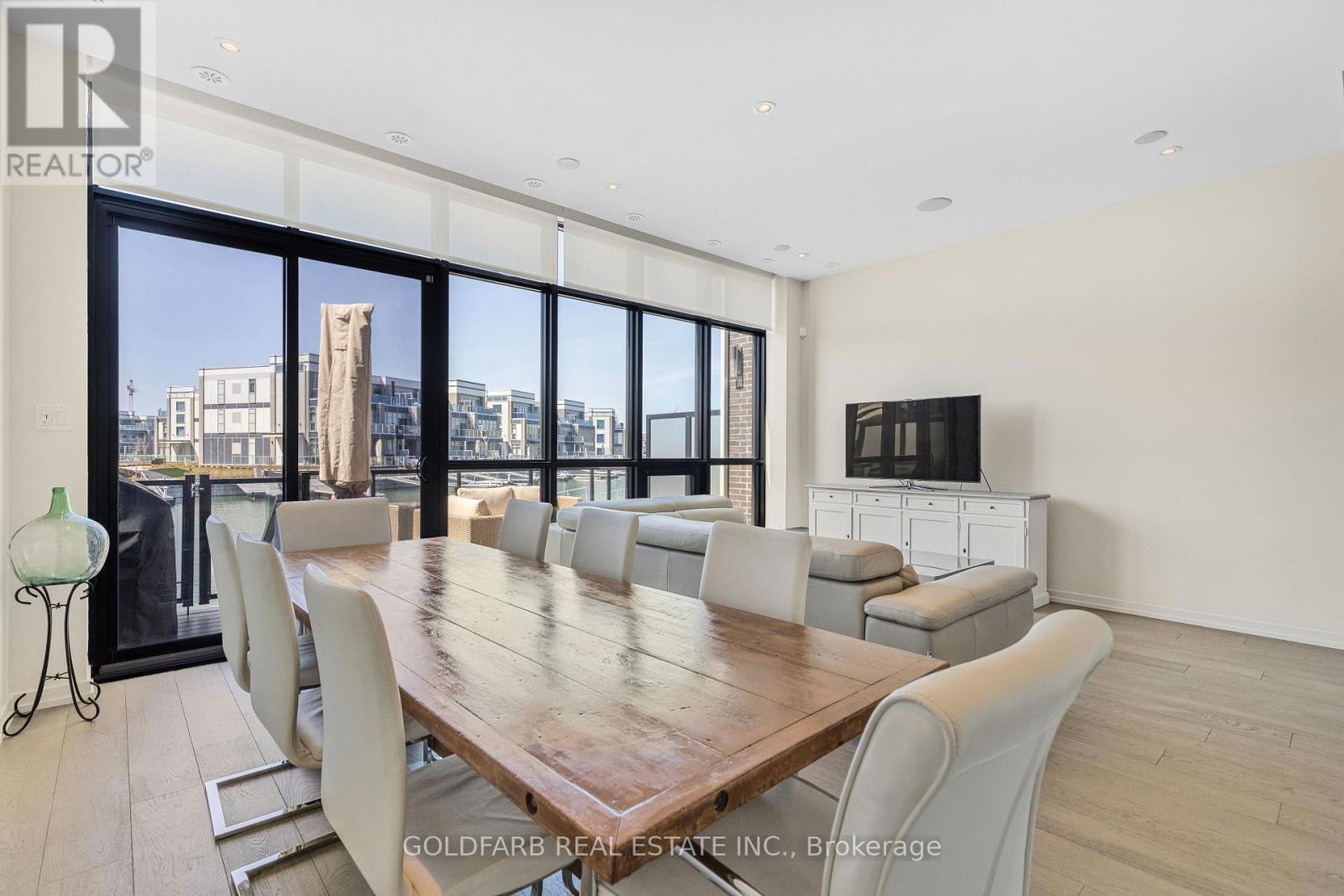 A dining room with a large table and chairs with a city view through the windows.