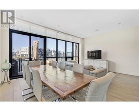 A dining room with a large table and chairs with a city view through the windows.