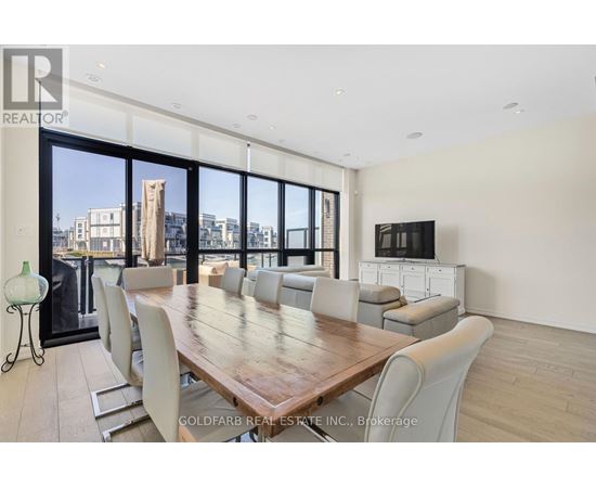 A dining room with a large table and chairs with a city view through the windows.
