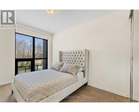 A bedroom with a large bed and a window overlooking a tree-lined area.