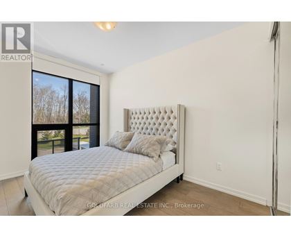 A bedroom with a large bed and a window overlooking a tree-lined area.