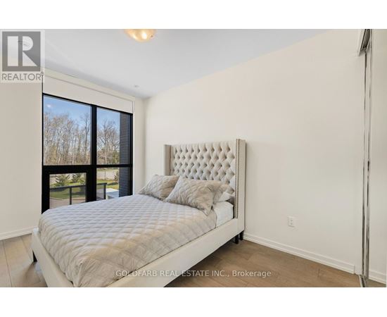 A bedroom with a large bed and a window overlooking a tree-lined area.