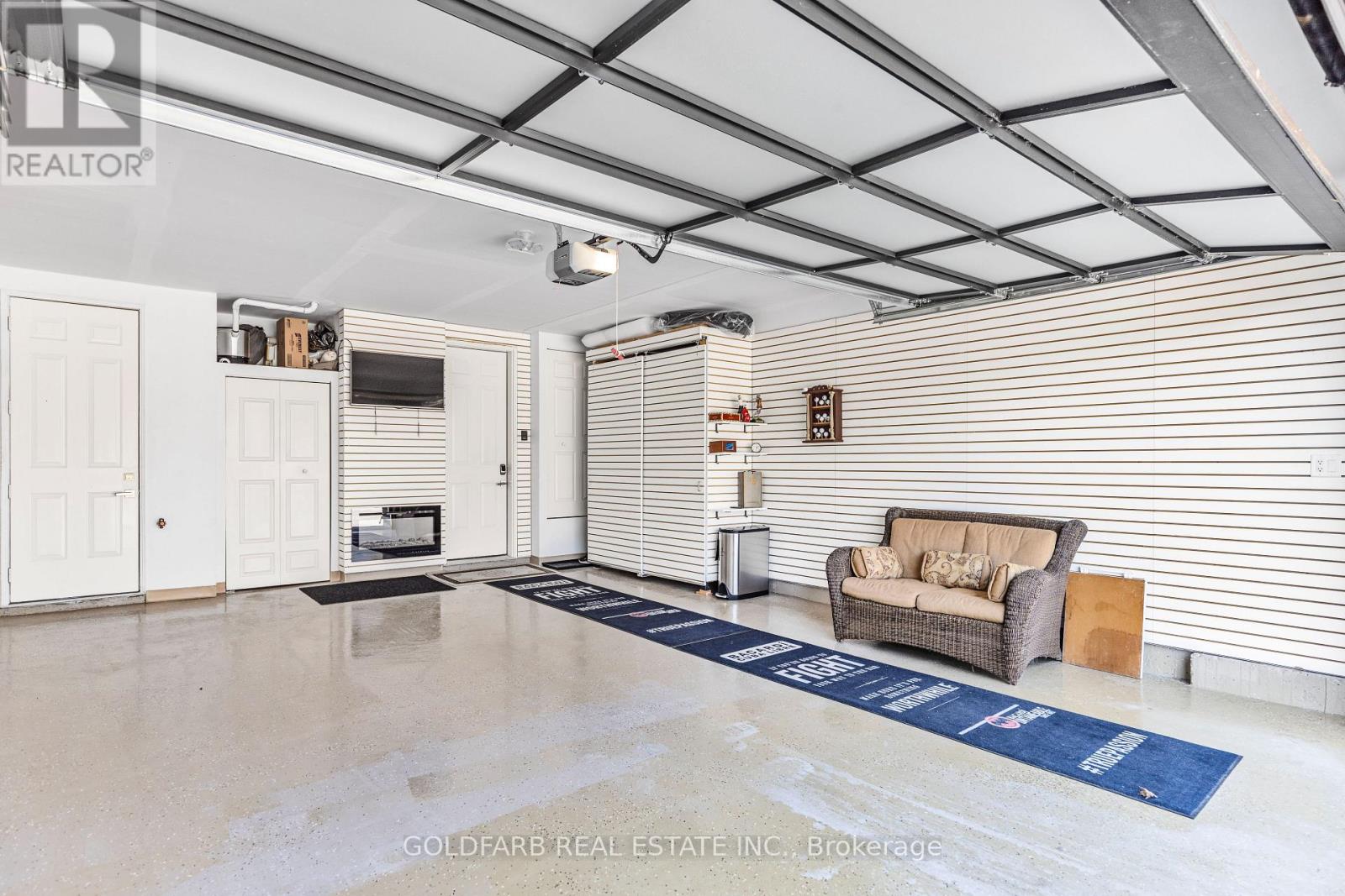 A spacious room with a couch, a television, and a blue rug on the floor.