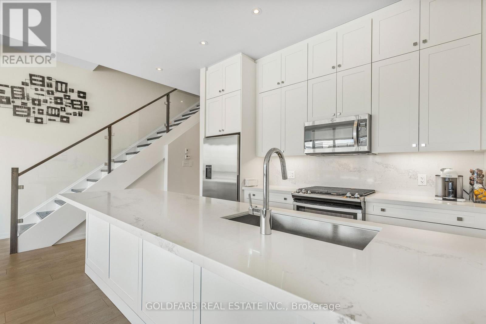 A modern kitchen with white cabinets and a stainless steel sink.