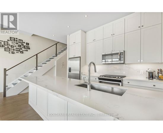 A modern kitchen with white cabinets and a stainless steel sink.