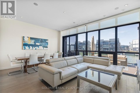 A living room with a large couch and a painting on the wall.