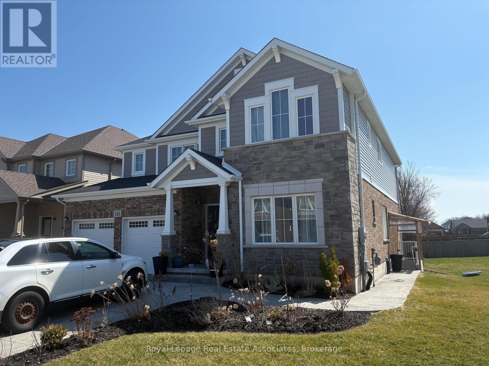 A white car is parked in front of a house with a sign that says "REALTOR".