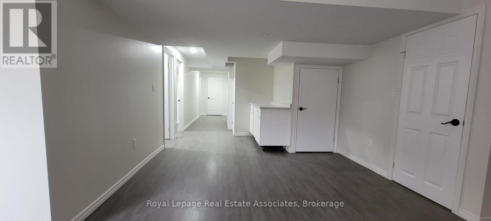 A long hallway with white doors and a white wall.