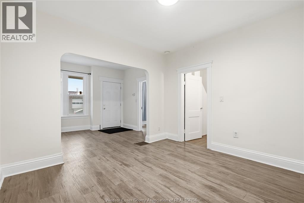 A spacious room with wooden flooring and white walls.
