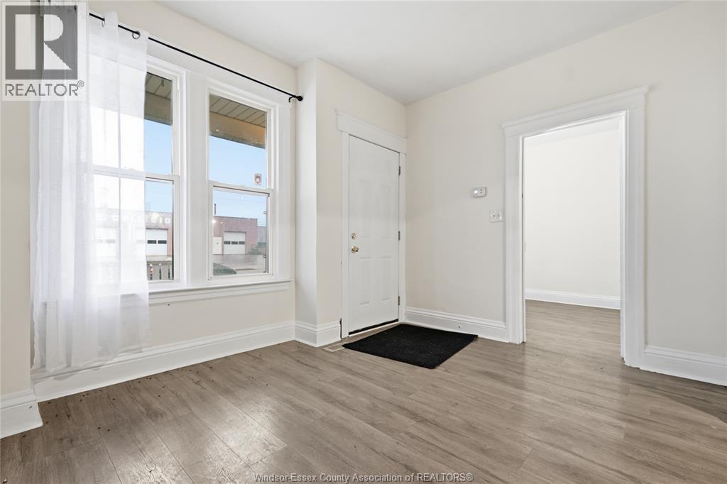 A room with a window, a door, and a mat on the floor.