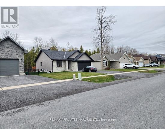 A residential street with houses and cars parked on the side.