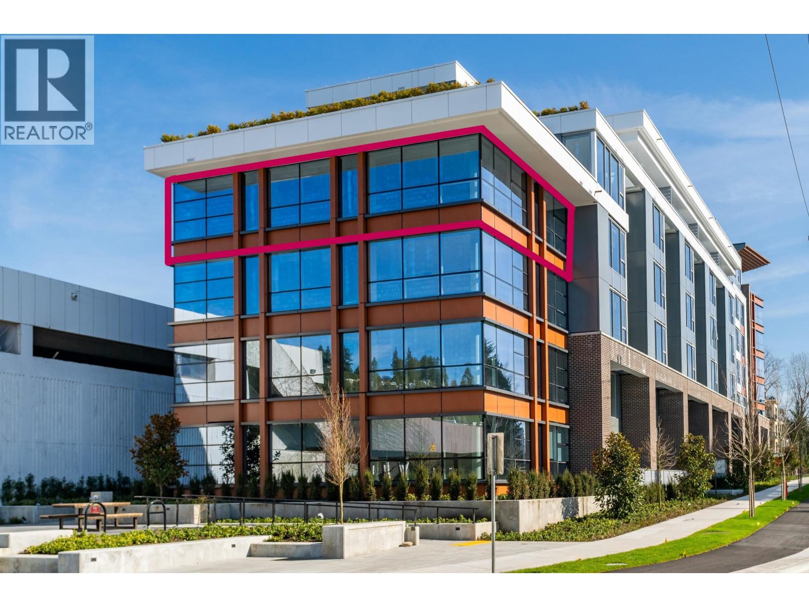 A modern multi-story building with a glass facade and a white exterior.