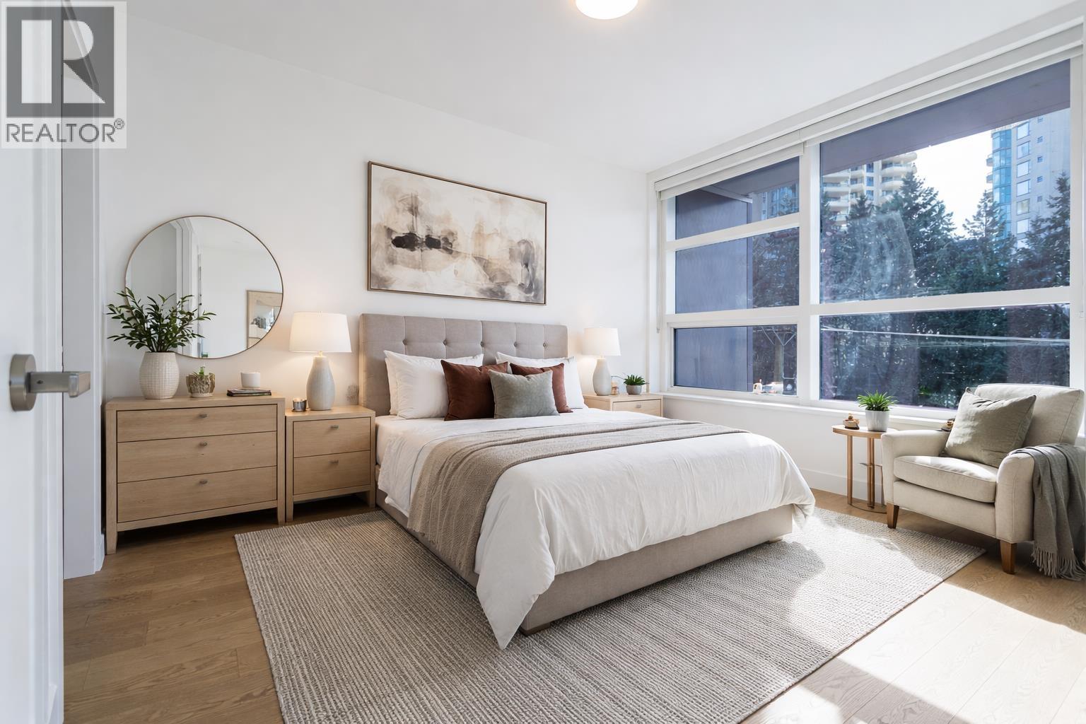 A bedroom with a large bed, a side table, and a chair.