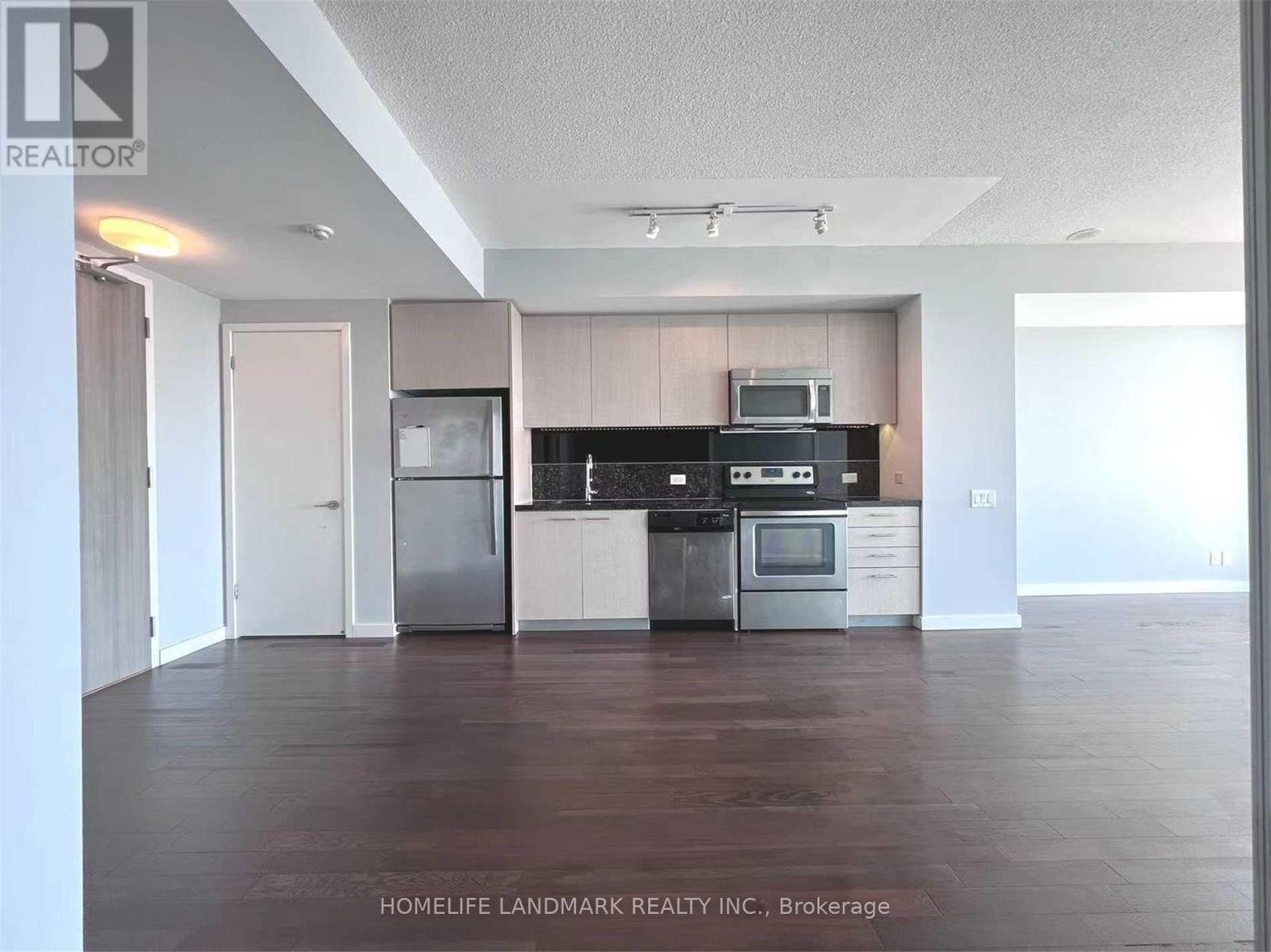 A kitchen with a refrigerator, oven, and microwave.