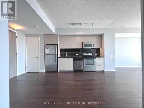 A kitchen with a refrigerator, oven, and microwave.