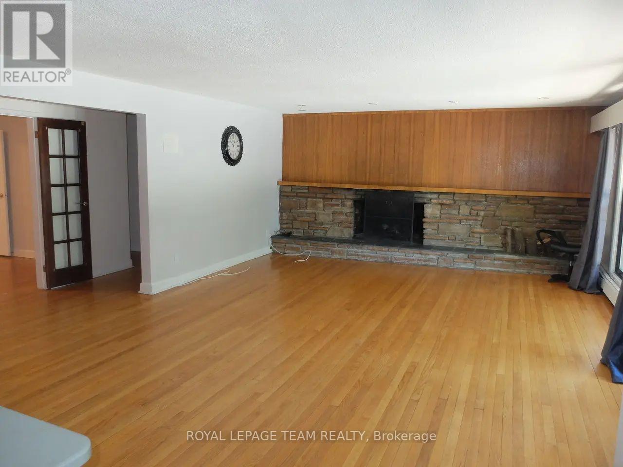 A living room with a fireplace and wooden floors.