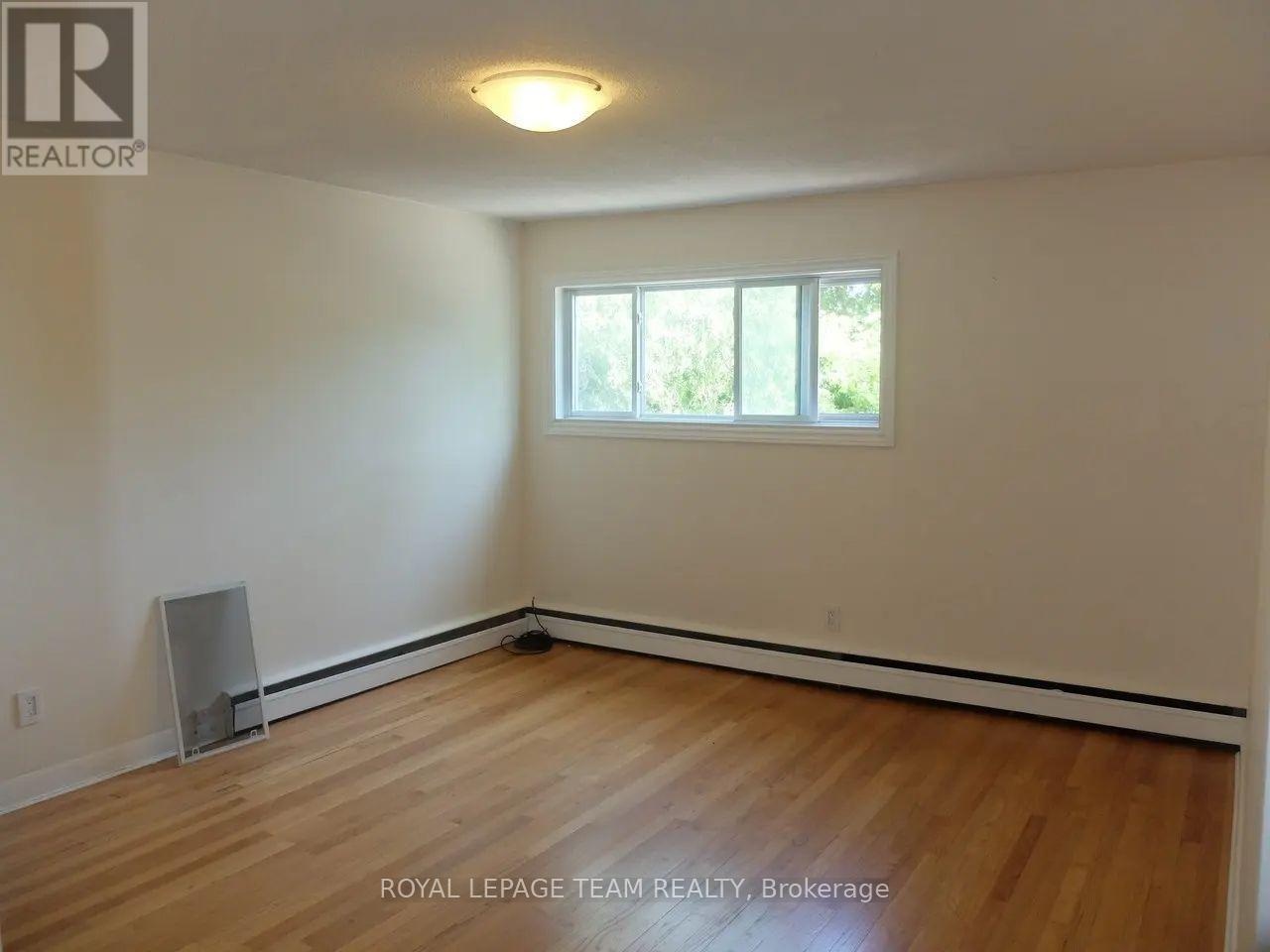 A room with wooden flooring and a window.