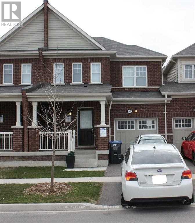 A white car is parked in front of a brick house.