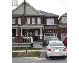 A white car is parked in front of a brick house.
