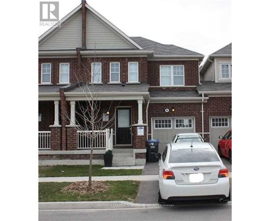 A white car is parked in front of a brick house.