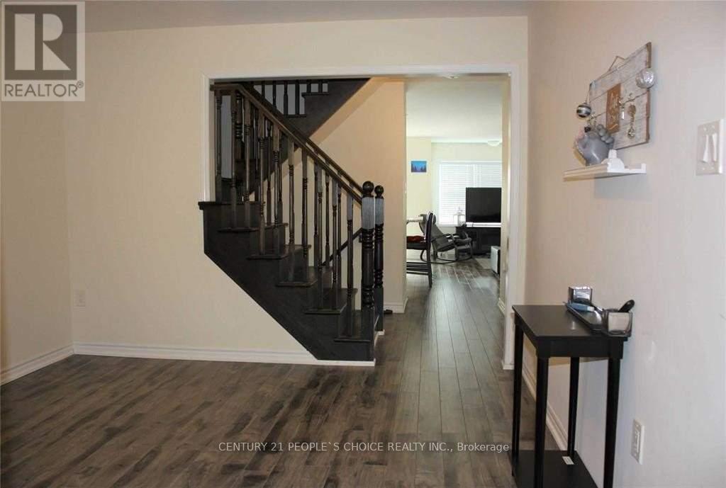 A room with a wooden floor and a staircase with a black railing.