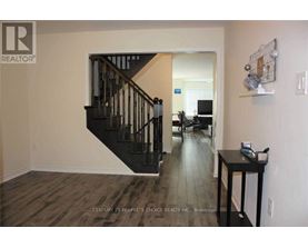 A room with a wooden floor and a staircase with a black railing.
