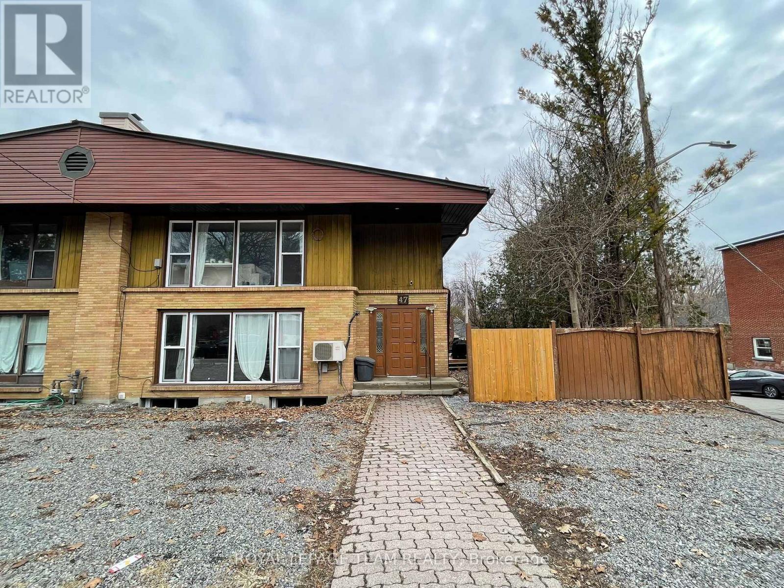 A house with a brown roof and a gravel driveway in front.