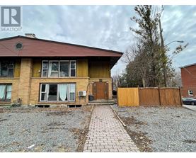 A house with a brown roof and a gravel driveway in front.