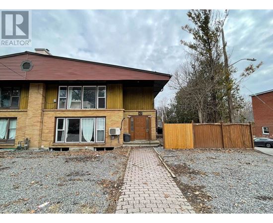 A house with a brown roof and a gravel driveway in front.