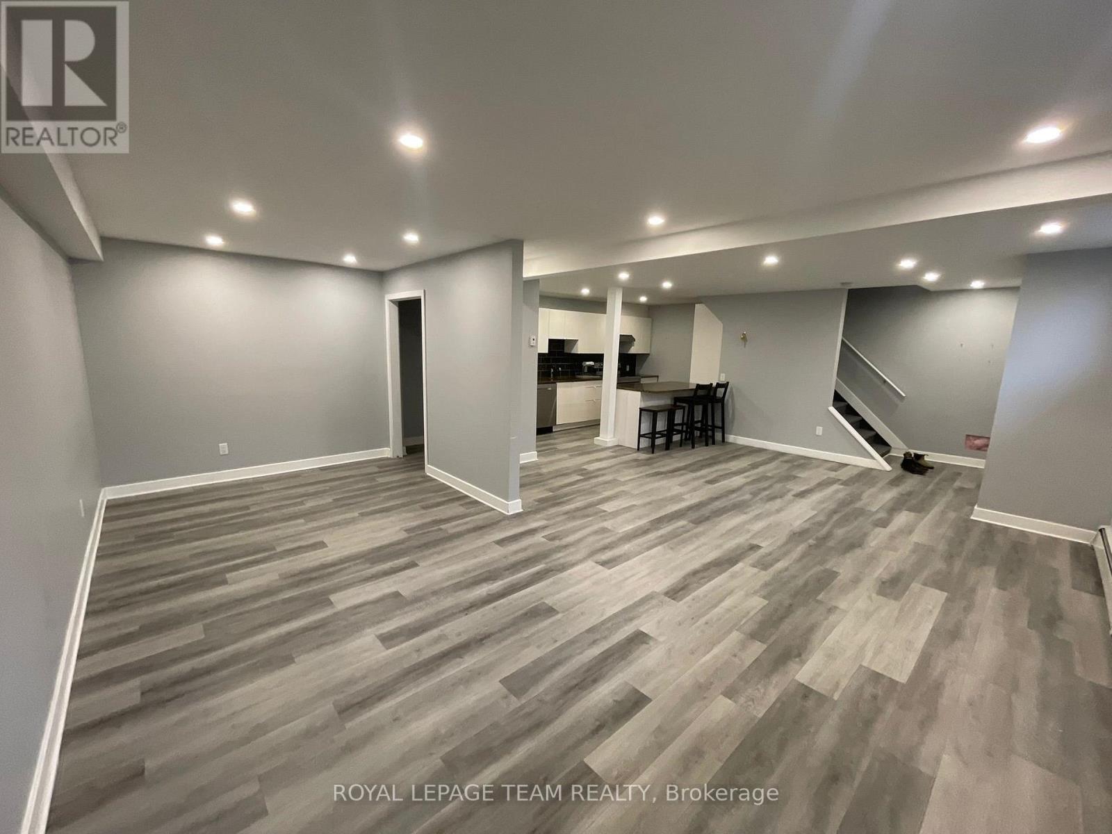 A spacious room with wooden flooring and a bar area in the corner.